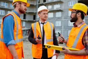 Three contractors in hard hat having a discussion about the safety protocols on-site